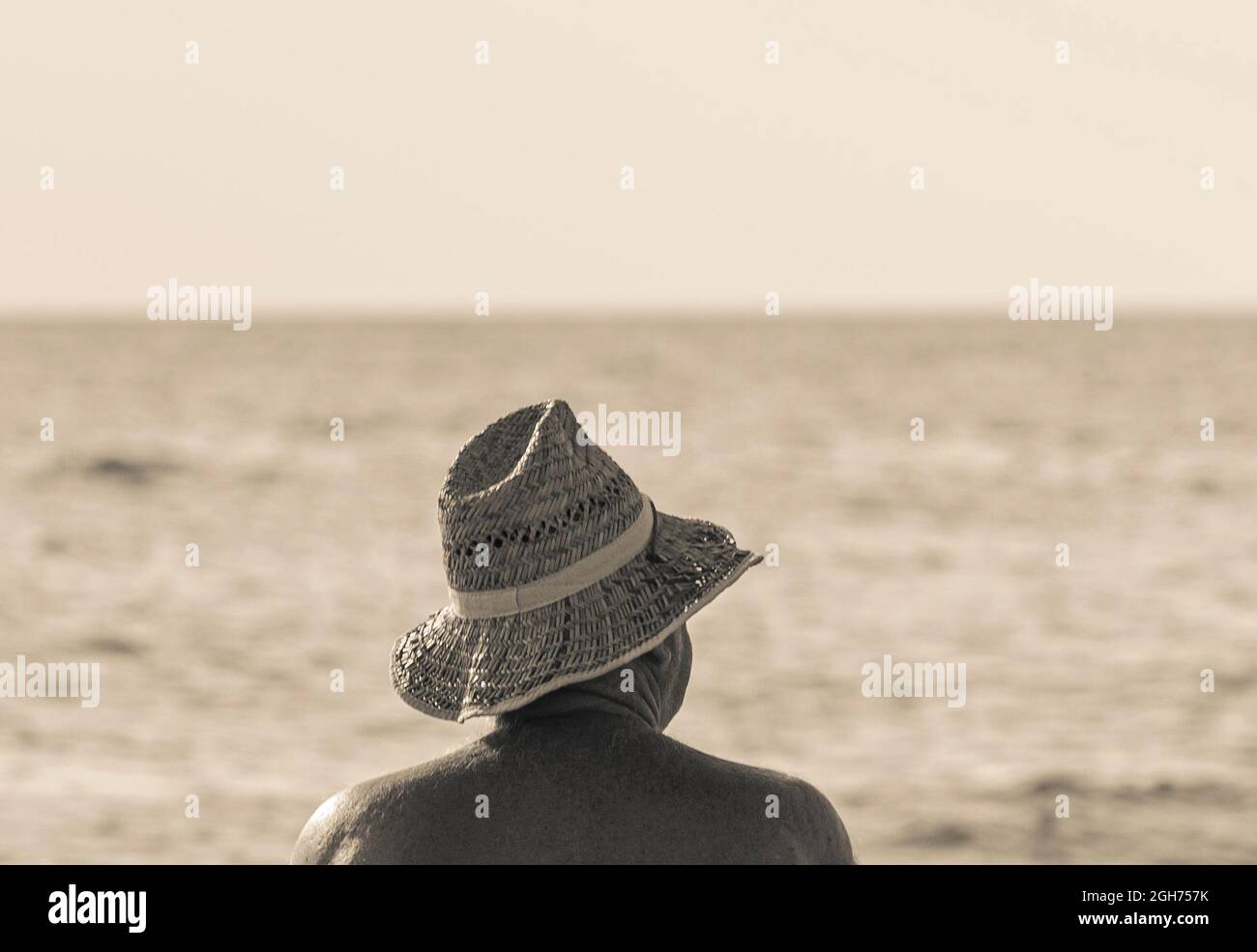 unrecognizable senior man wears straw hat sunbathing at sea beach, black- white photo Stock Photo