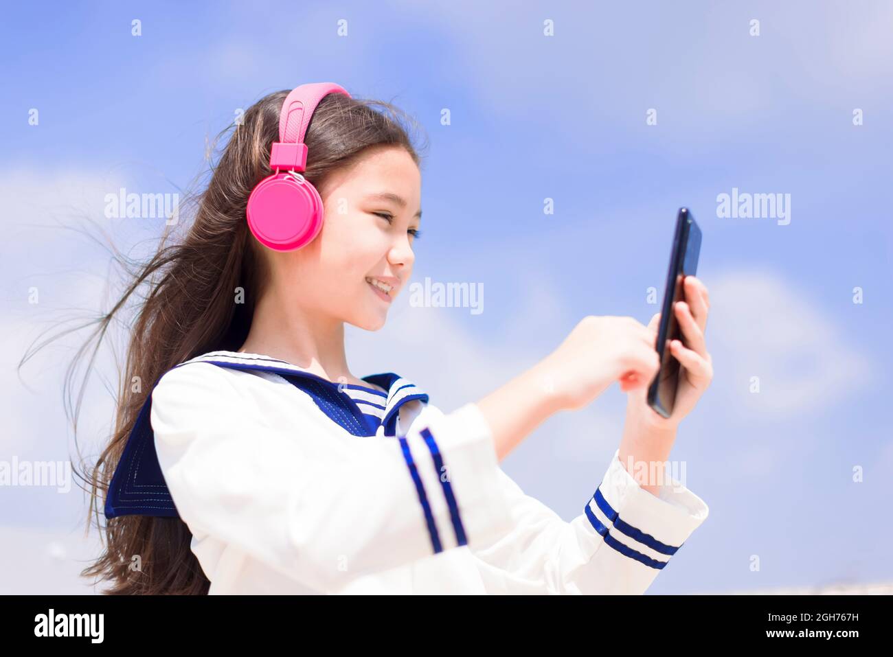 Happy student girl  listening music in headphones, holding mobile phone Stock Photo