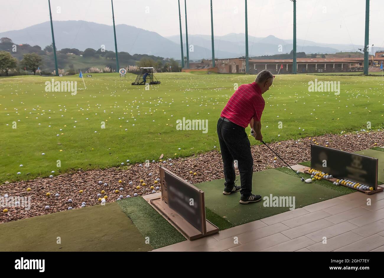 Man hits ball on golf driving range, Mexico City, Mexico Stock Photo
