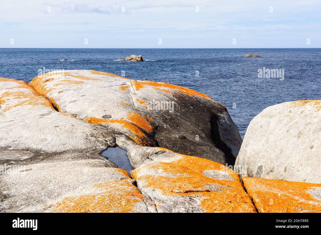 Orange lichen-covered granite boulders in Bay of Fires - The Gardens, Tasmania, Australia Stock Photo