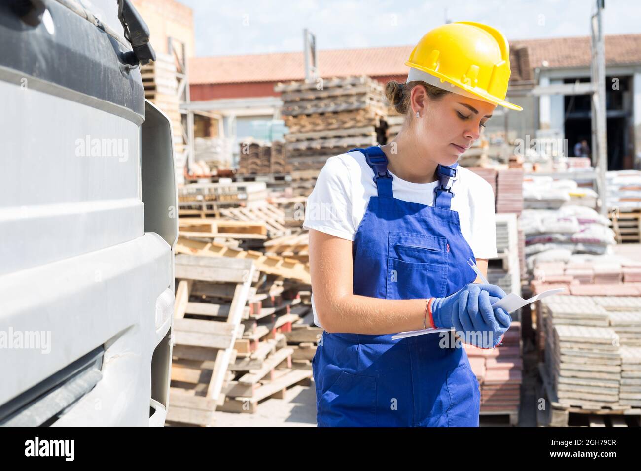Female driver keeps records of materials when loading into back of truck at site of hardware store Stock Photo