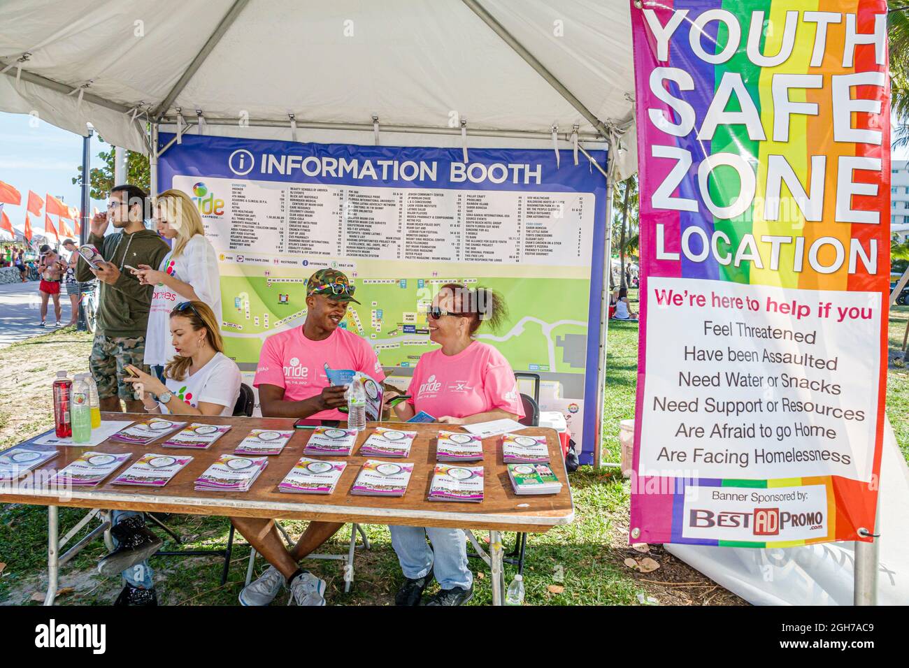 Miami Beach Florida,Gay Pride Week LGBTQ LGBT Pride Festival booth table vendor,Youth Safe Zone,Black man woman volunteers helping volunteering teamwo Stock Photo