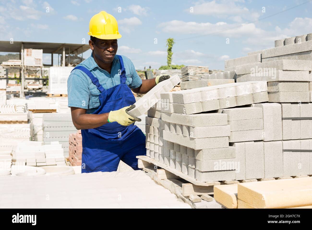Builder carrying concrete block in outdoor warehouse Stock Photo