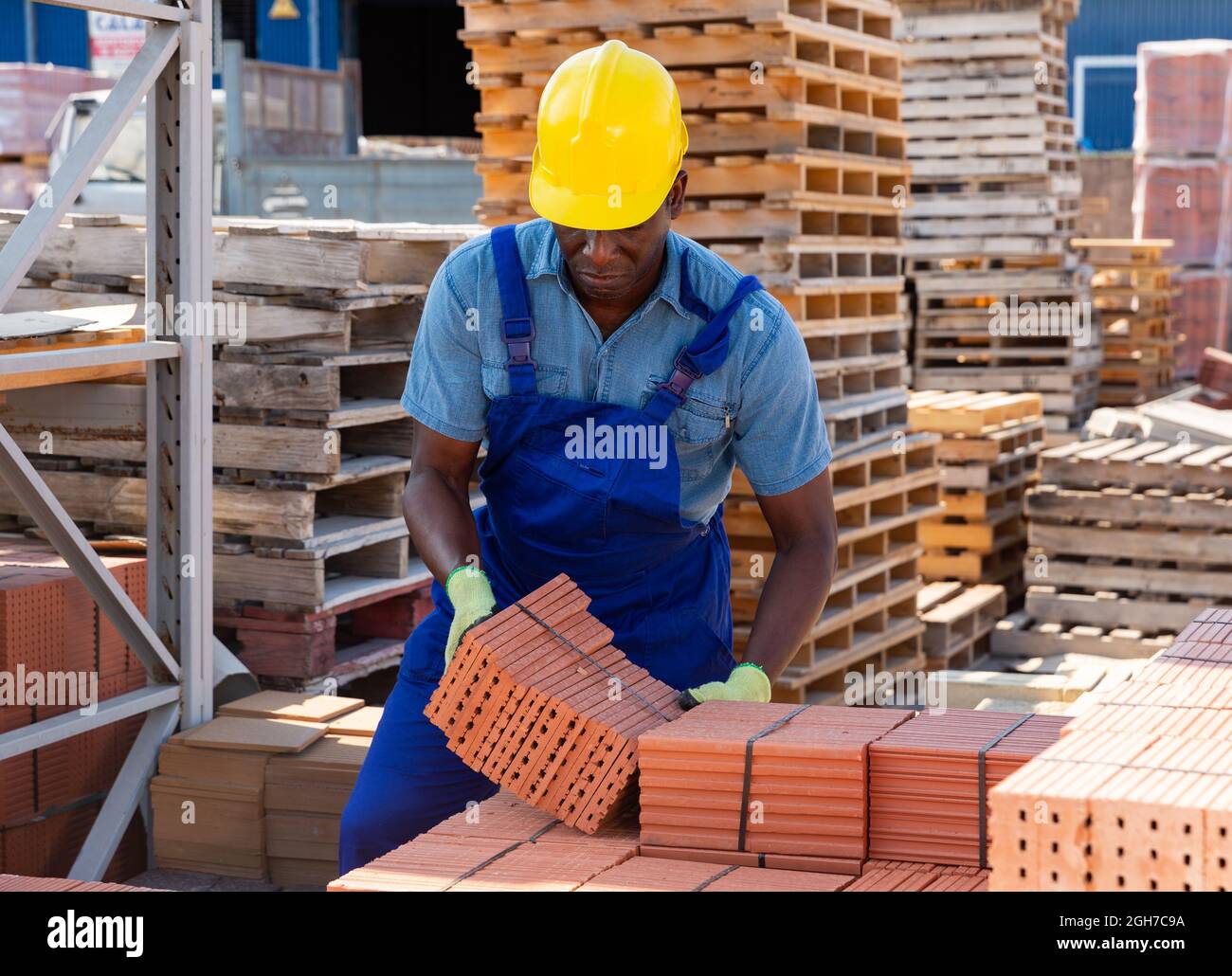 Worker stacking bricks in warehouse of building materials clpseup Stock
