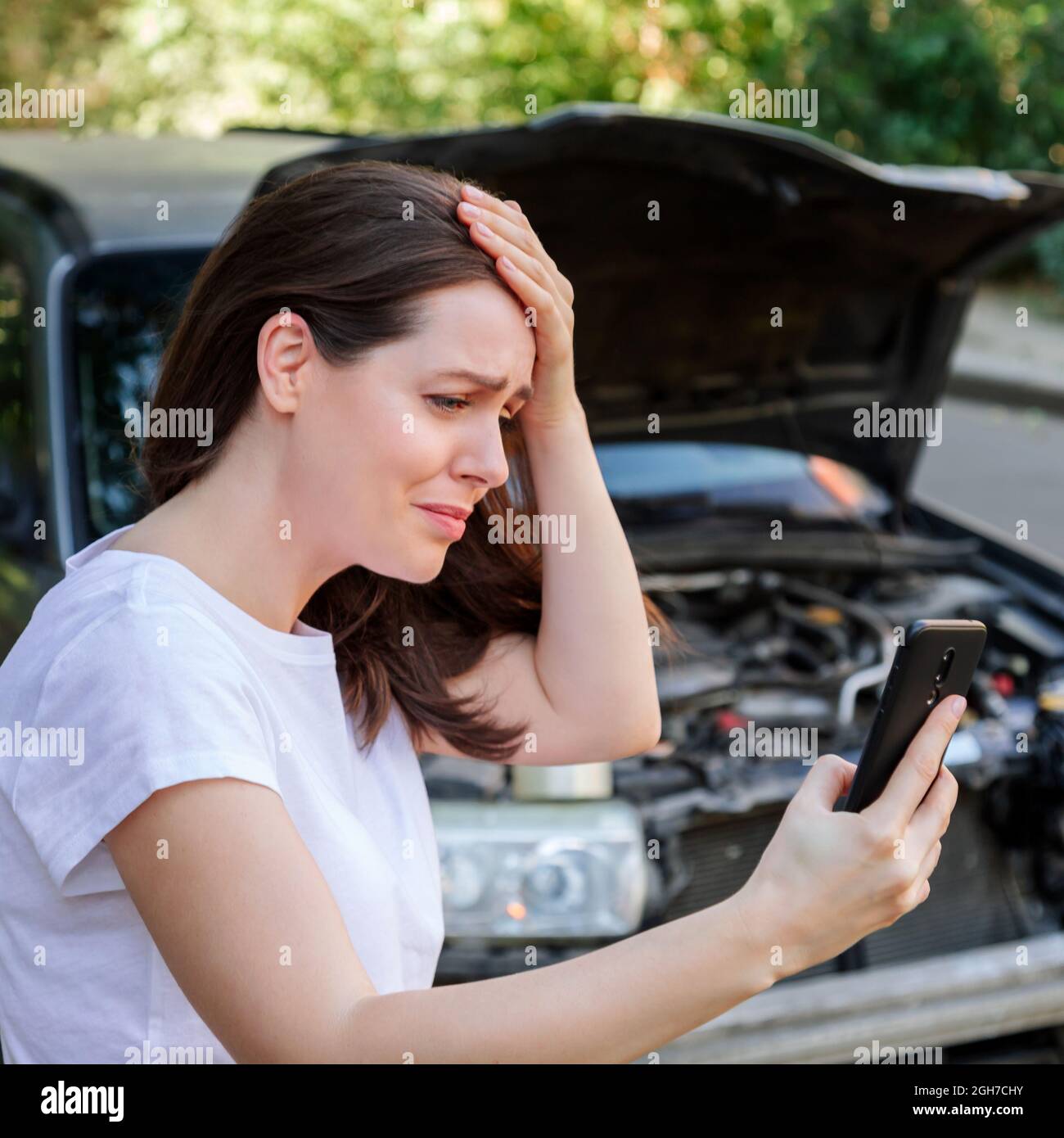 Scared woman in stress holding her head after auto crash calling to auto insurance for help. Driver woman portrait in front of wrecked car in car Stock Photo