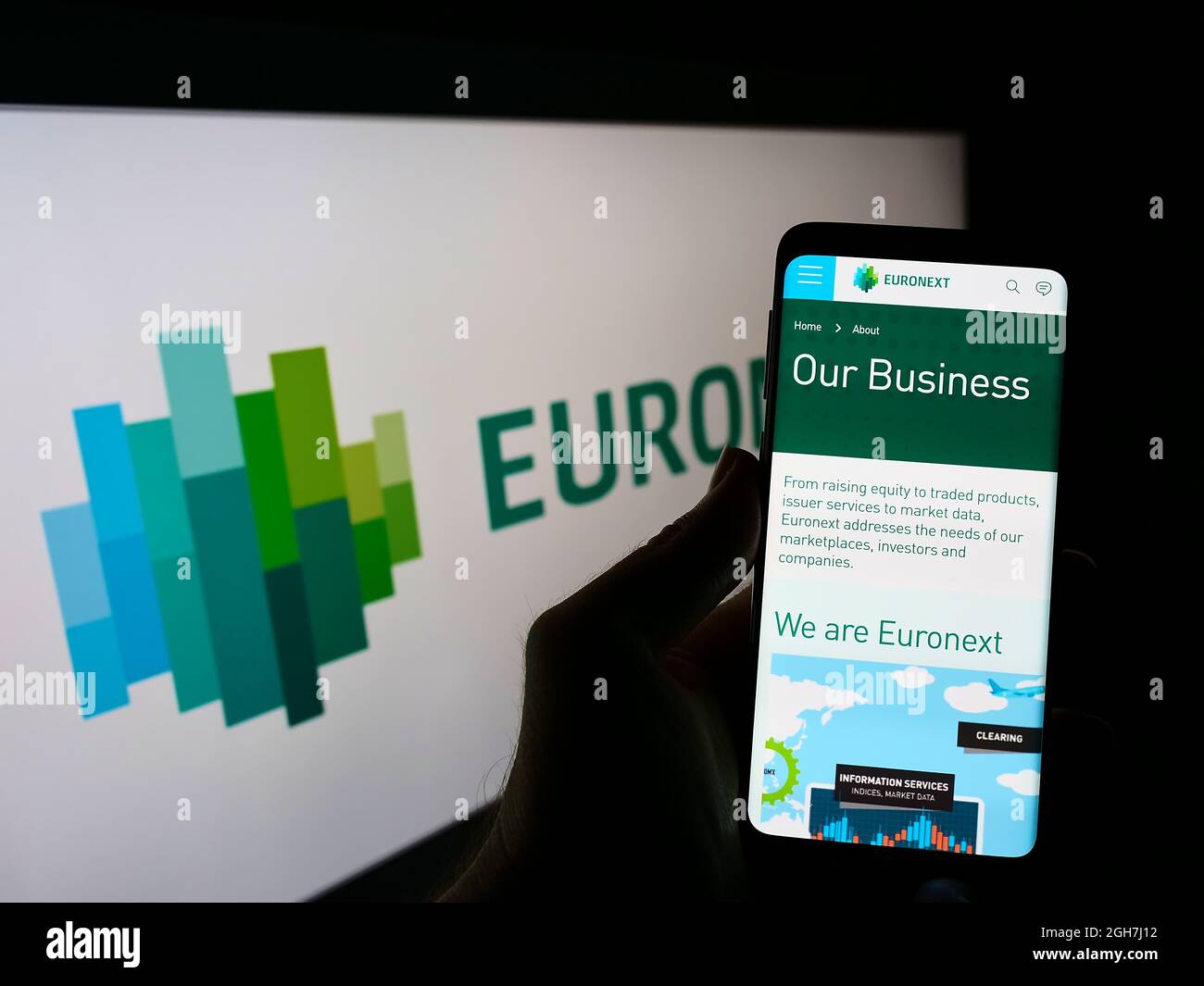 Person holding mobile phone with webpage of financial services company Euronext N.V. on screen in front of logo. Focus on center of phone display. Stock Photo