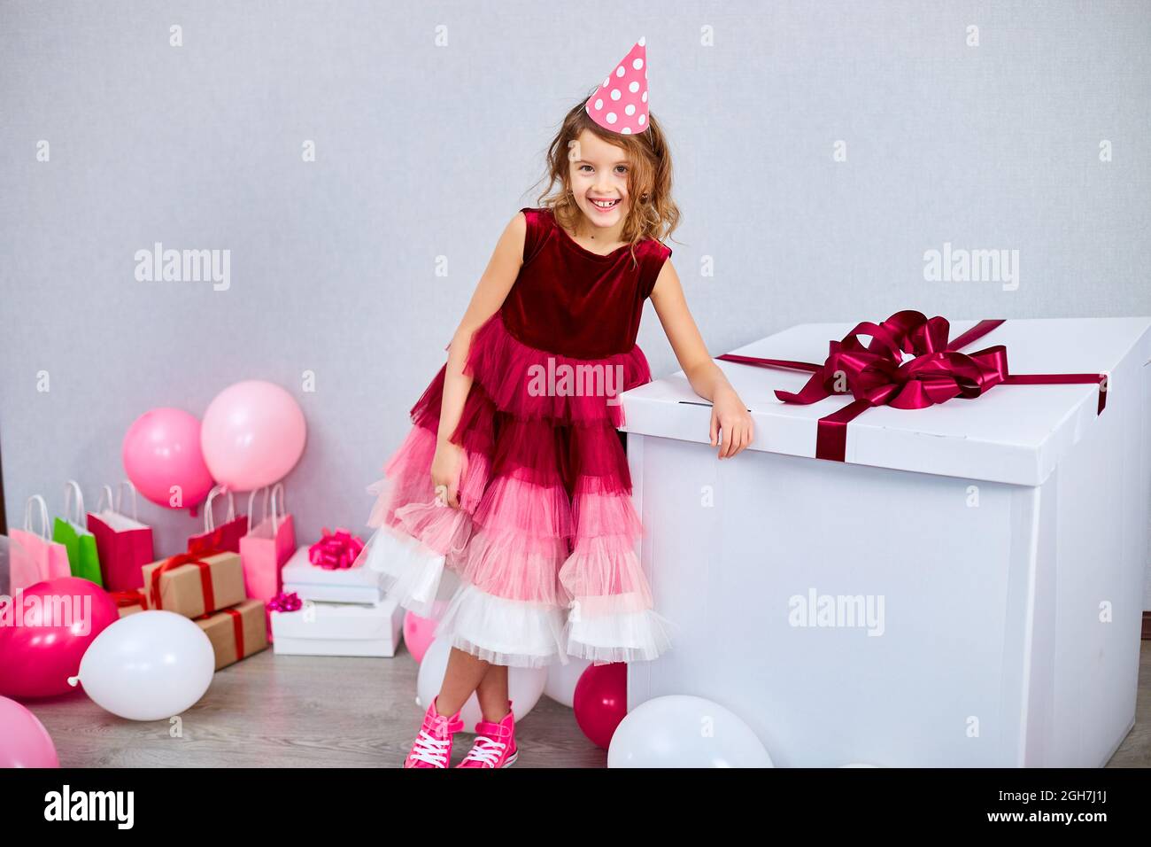 Joyful little girl in pink dress and sneakers with big present gift box,  balloons at home birthday party streamers, Happy birthday. Celebrating  Stock Photo - Alamy