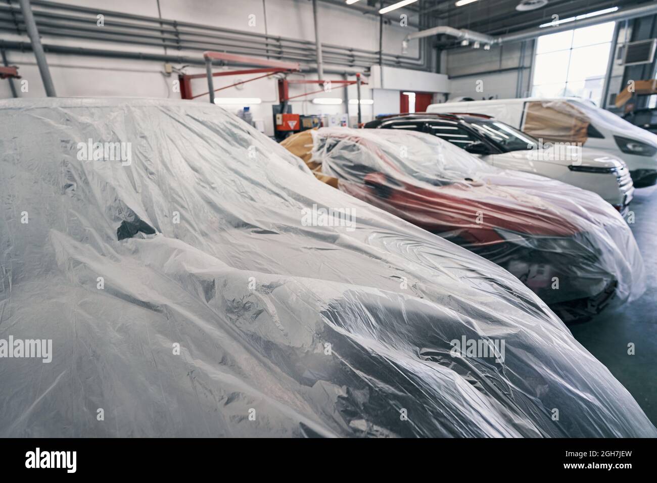 Cars standing in line with dustsheets on them Stock Photo