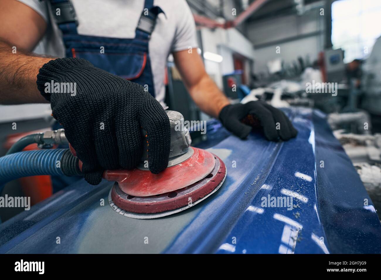 Repair shop worker sanding car with grinding machine Stock Photo