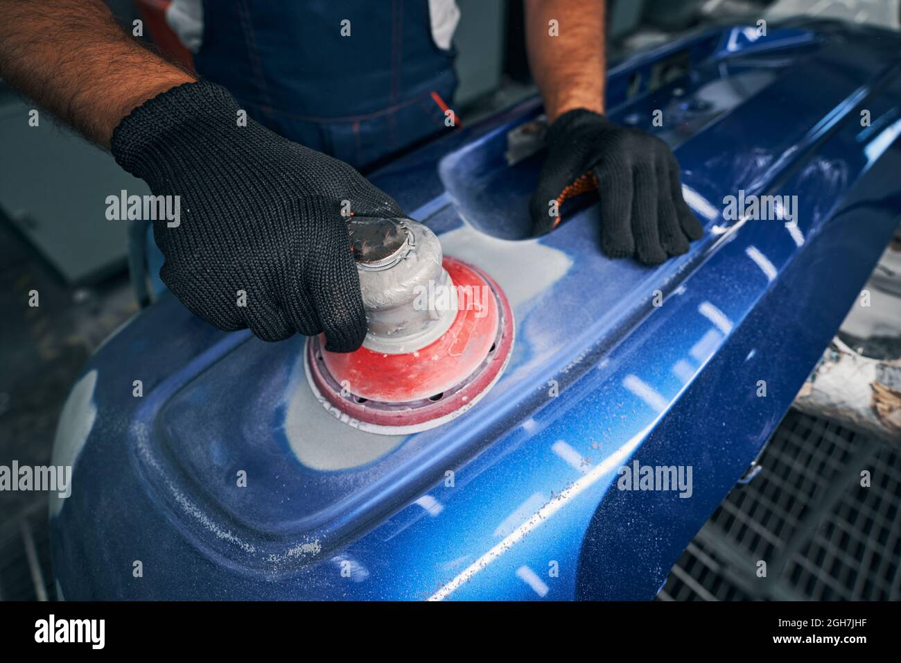 Mechanic using grinding unit on blue bumper Stock Photo