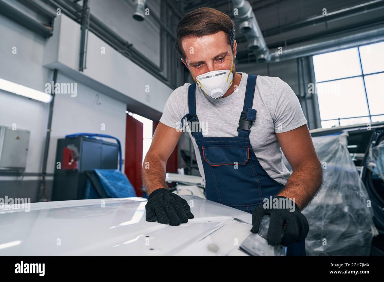 Worker of car paint workshop using hand sander Stock Photo