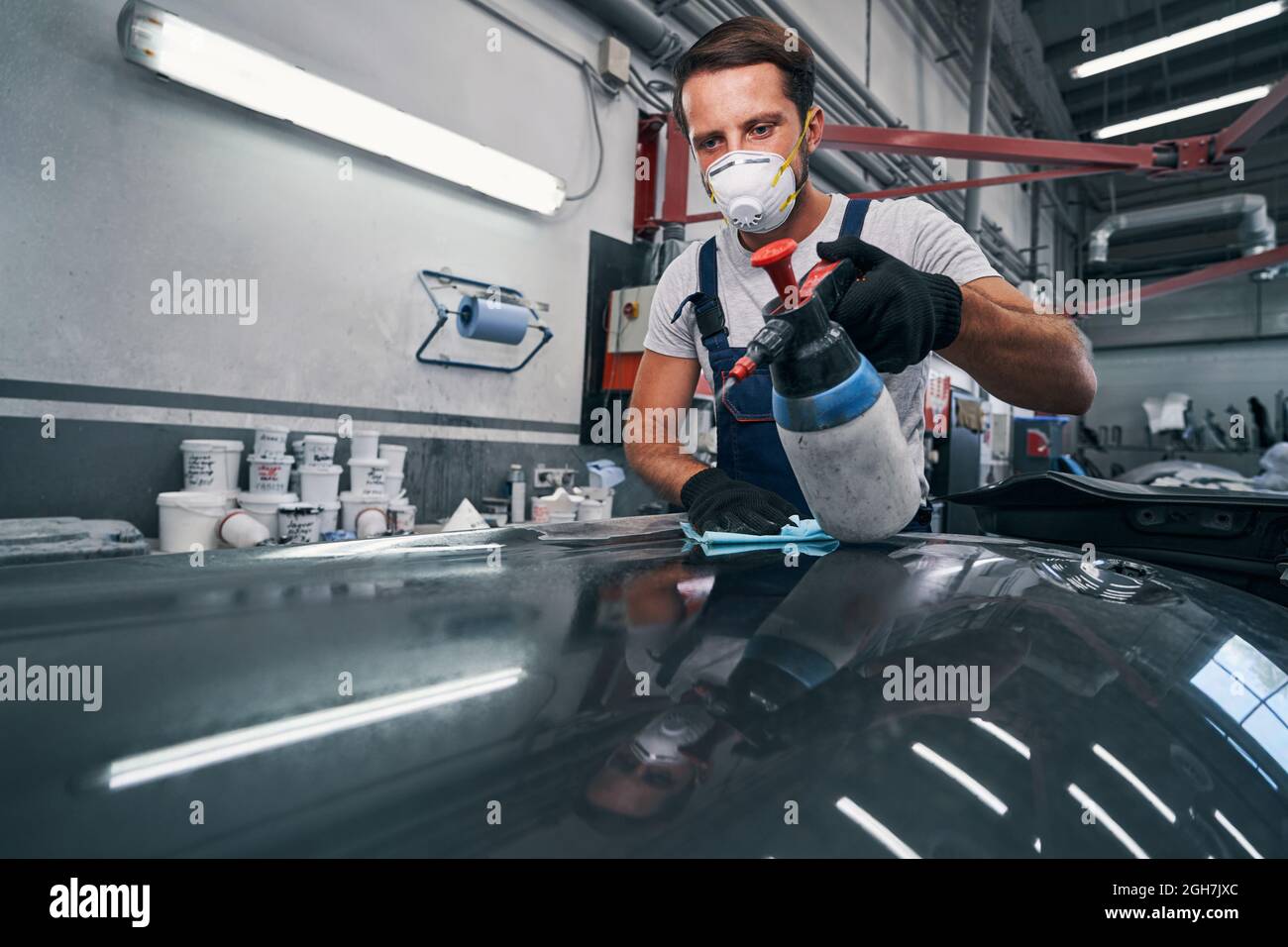 Car mechanic spraying surface from plastic container Stock Photo