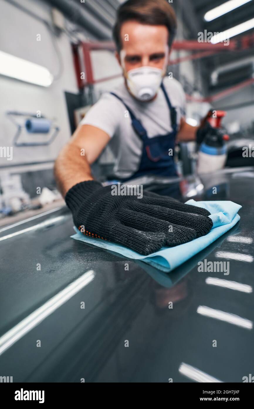 Hand pressing cloth to automobile surface while cleaning Stock Photo