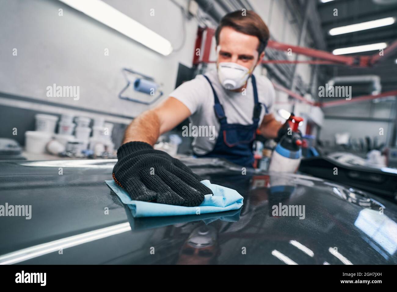 Hard-working male cleaning car in auto repair shop Stock Photo