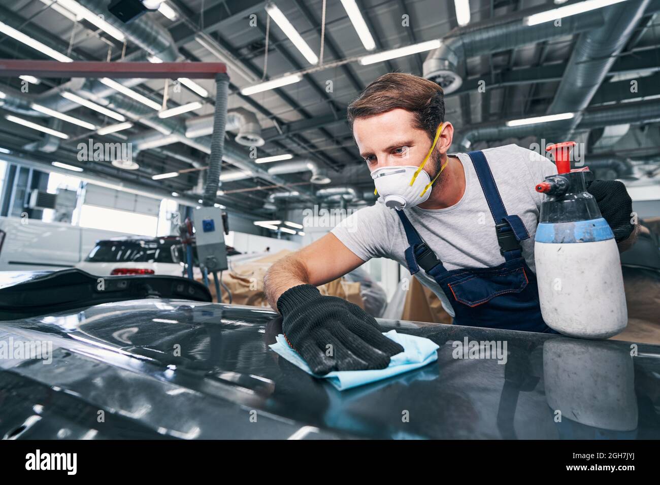 Focused man wiping automobile with cleaning cloth Stock Photo