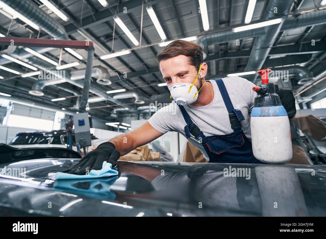 Automobile mechanic wiping dust off a car with cloth Stock Photo