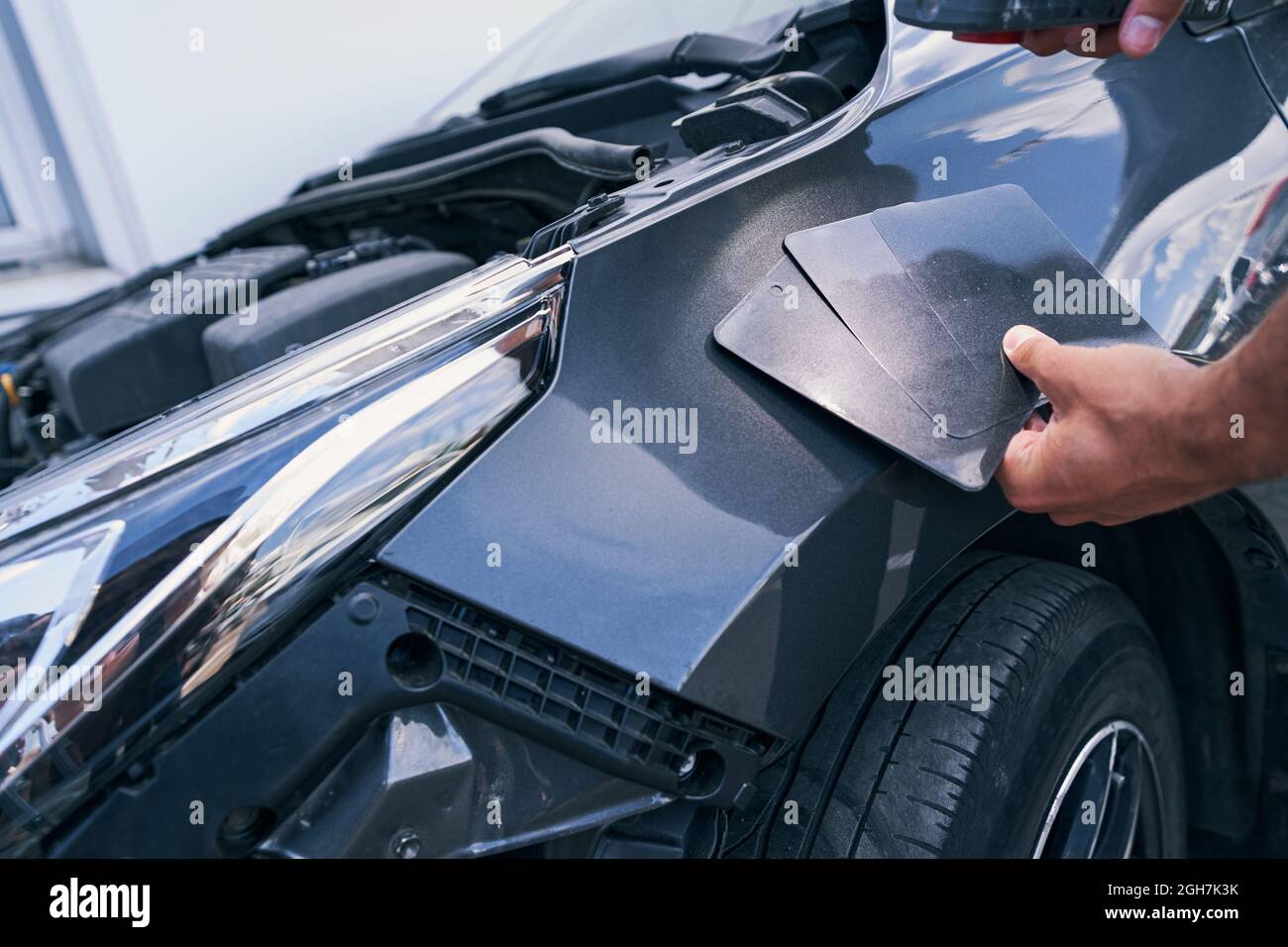 Car workshop employee putting colour samples on automobile surface Stock Photo