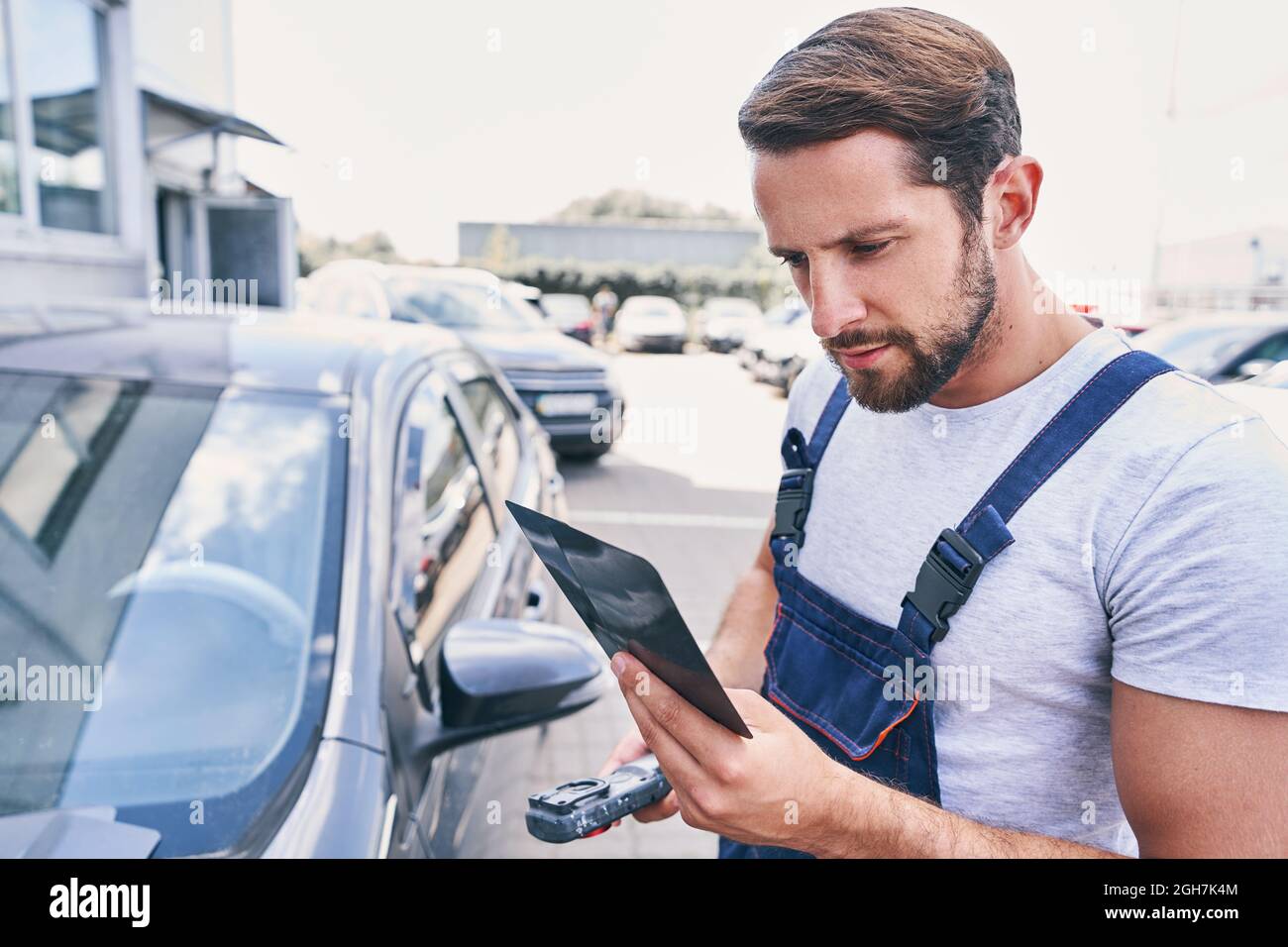 Professional repairman checking shades cards for car painting outdoors Stock Photo