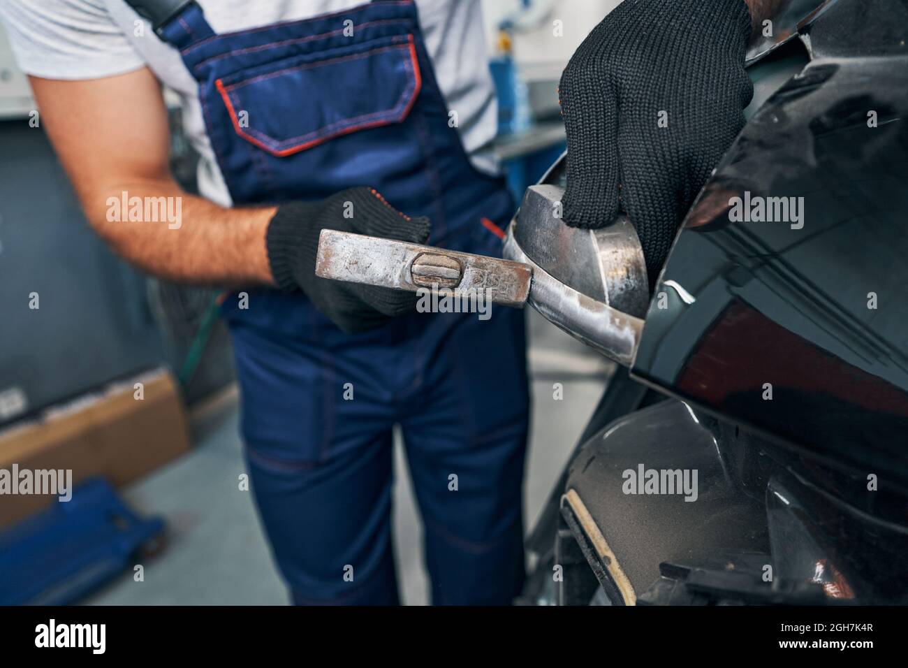 Auto mechanic peening car body surface with hammer Stock Photo