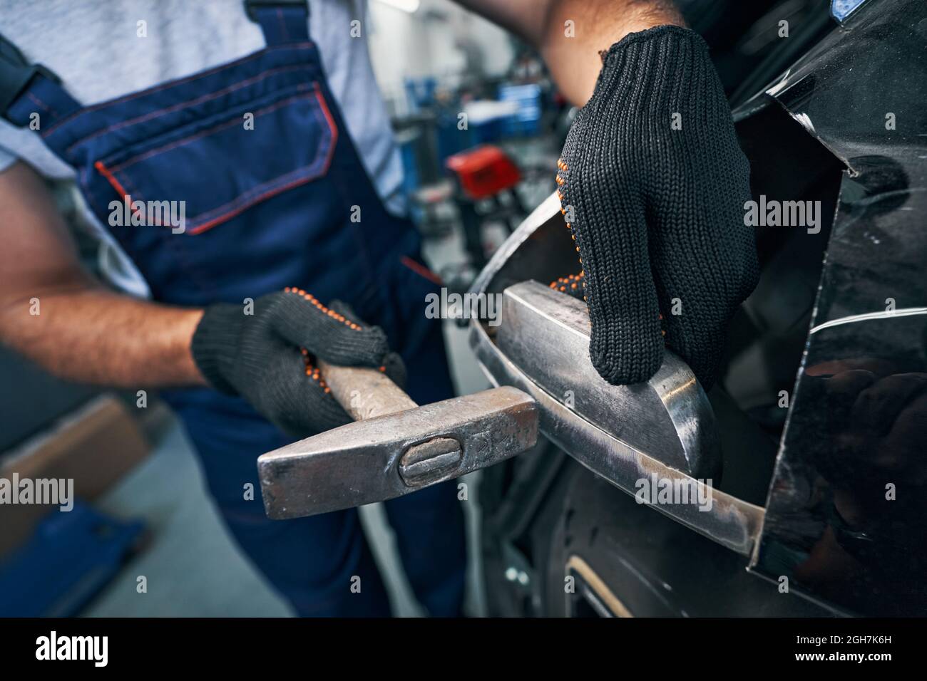 Repairman peening car detail with hammer in workshop Stock Photo