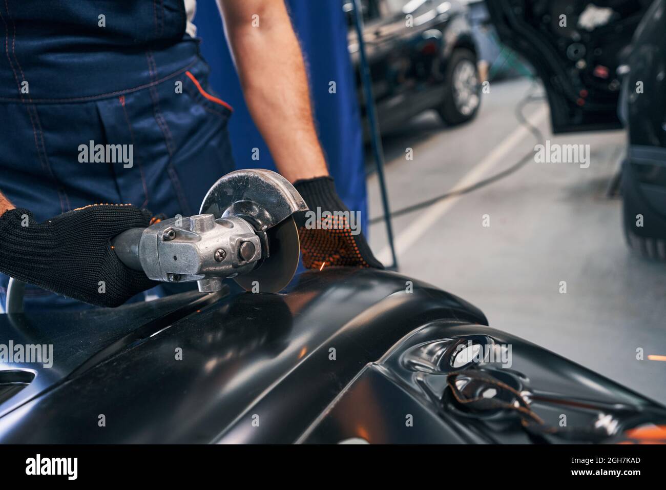 Repairmen cutting metal of car spare part with angle grinder Stock Photo