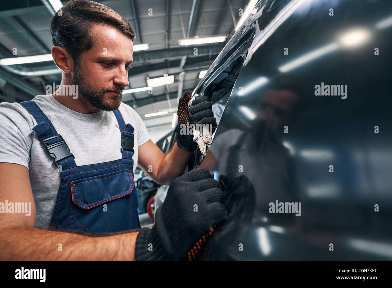 Auto mechanic using vice grip on car external detail Stock Photo