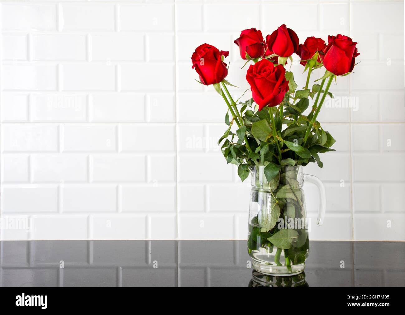 Red Roses Counter Beautiful red roses in a glass jug on black granite kitchen counter and ...
