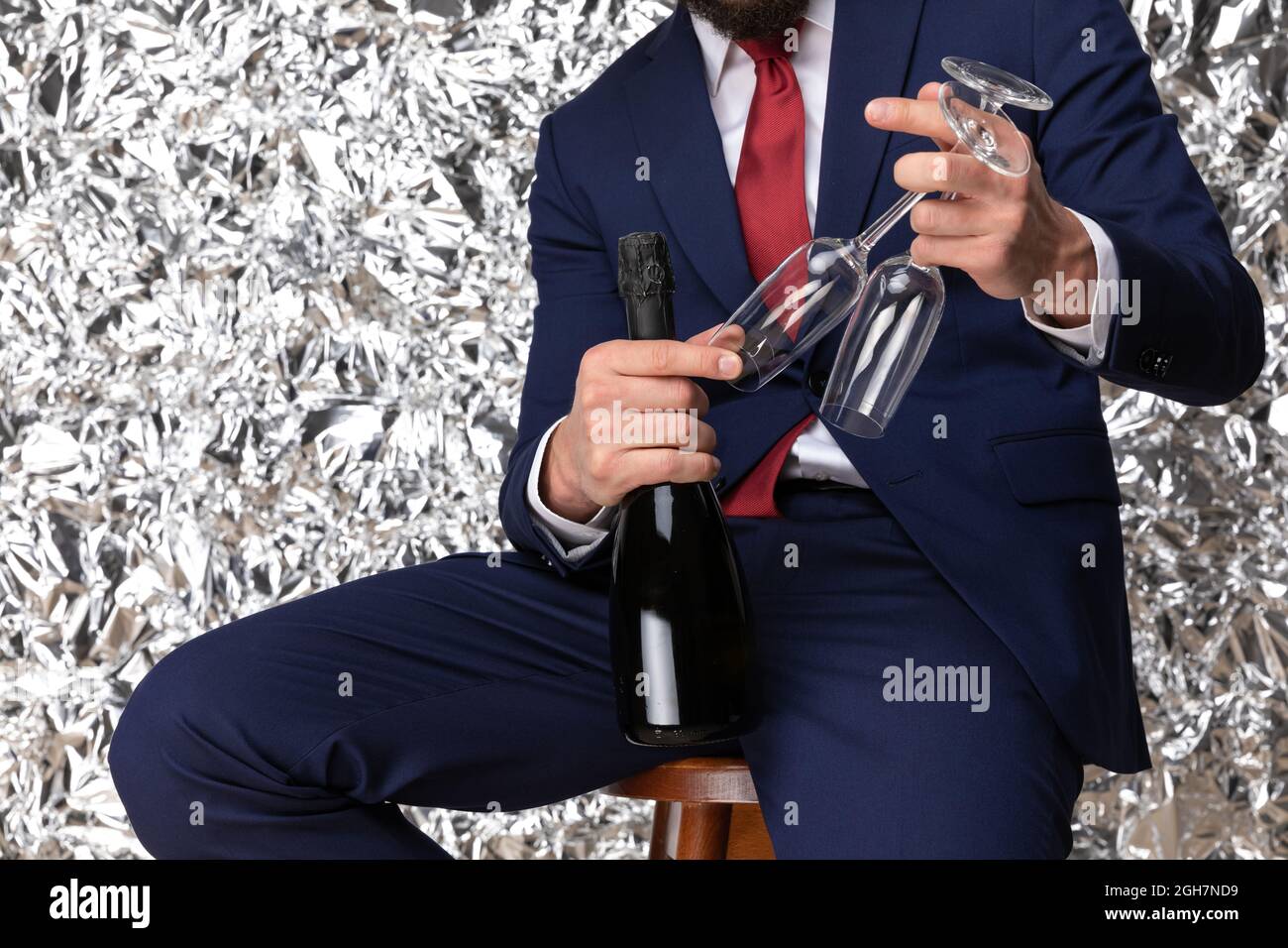 elegant businessman in navy blue suit recommending champagne bottle,  holding glasses and posing in front of tinfoil background in studio Stock  Photo - Alamy