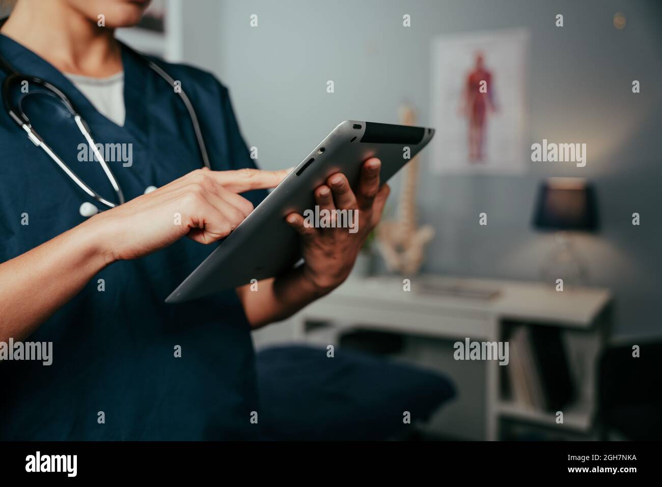 Close up female doctor researching in clinic typing on digital tablet Stock Photo