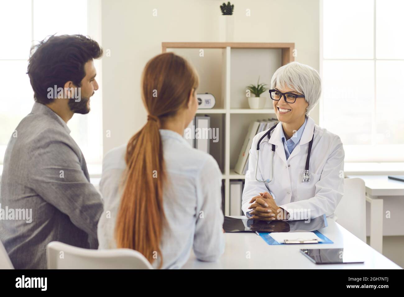 Happy husband and wife who are planning pregnancy are talking to their family doctor Stock Photo