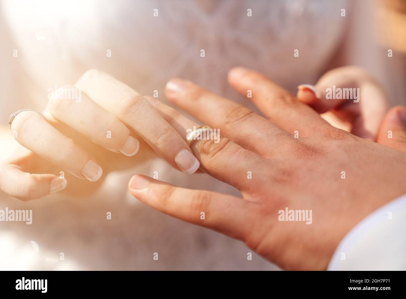 Bride and groom hands together and bride put wedding ring to grooms hand as a symbol of bonding. High quality photo Stock Photo