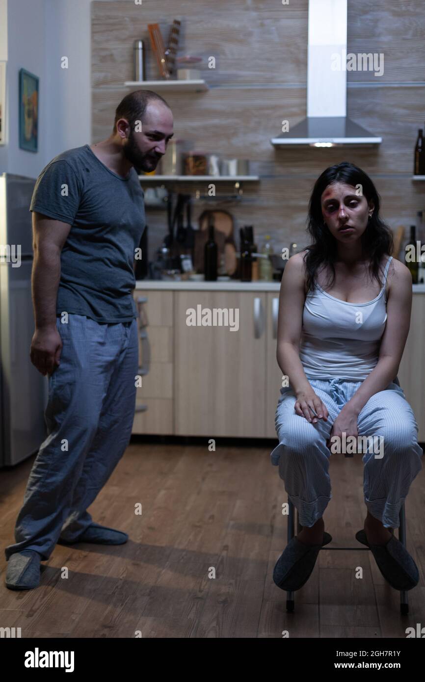 Angry violent man threatening unhappy abused woman with bruises on face. Alcoholic aggressive husband shouting at depressed wife being victim of domestic violence and physical trauma Stock Photo