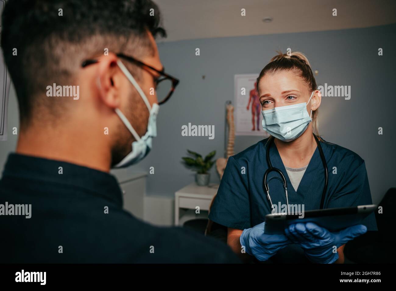 female nurse chatting to mixed race male patient Stock Photo