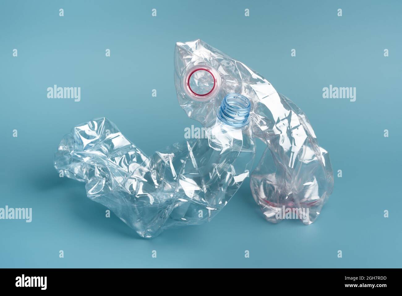 Composition of two used crushed plastic bottles on the blue background. Recycling concept. Stock Photo