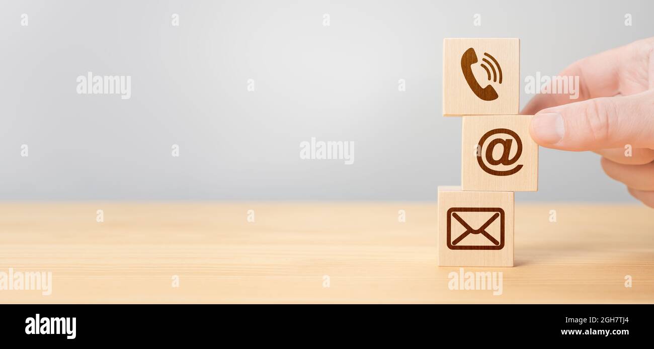 Hand Stacking wood Blocks with Icons mobile phone, email envelope telephone and e-mail address Against gray Background. Wooden cubes with symbol telep Stock Photo