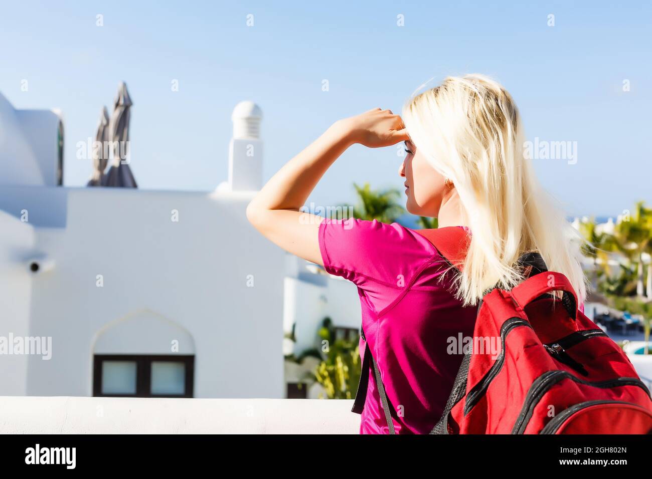 Back view of a young woman traveler with a backpack on her shoulder out ...