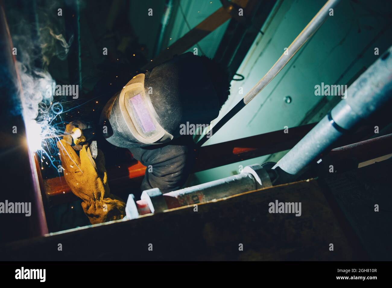 Young male welder worker using welding torch while working at site Stock Photo