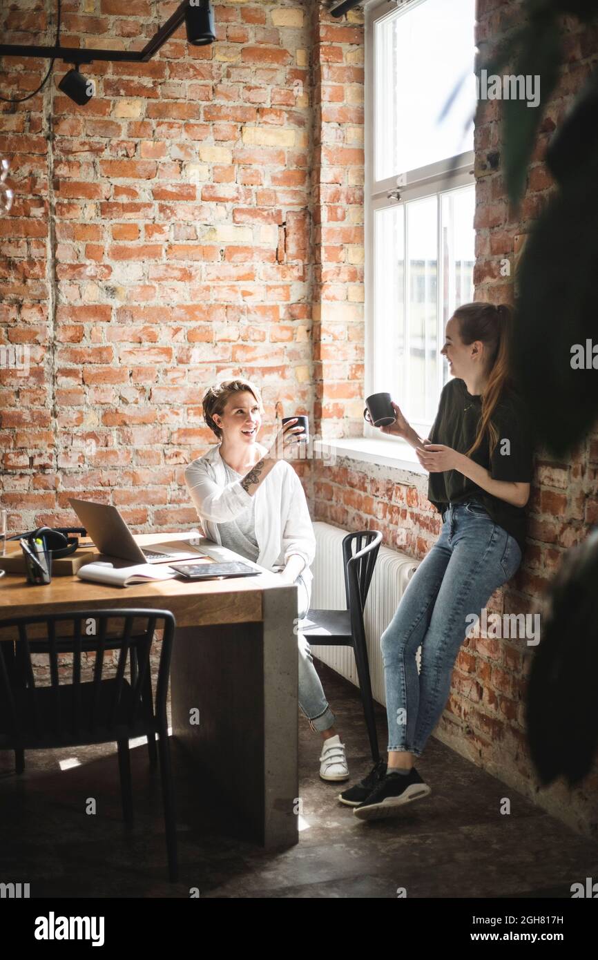 Happy female colleagues having coffee in office Stock Photo