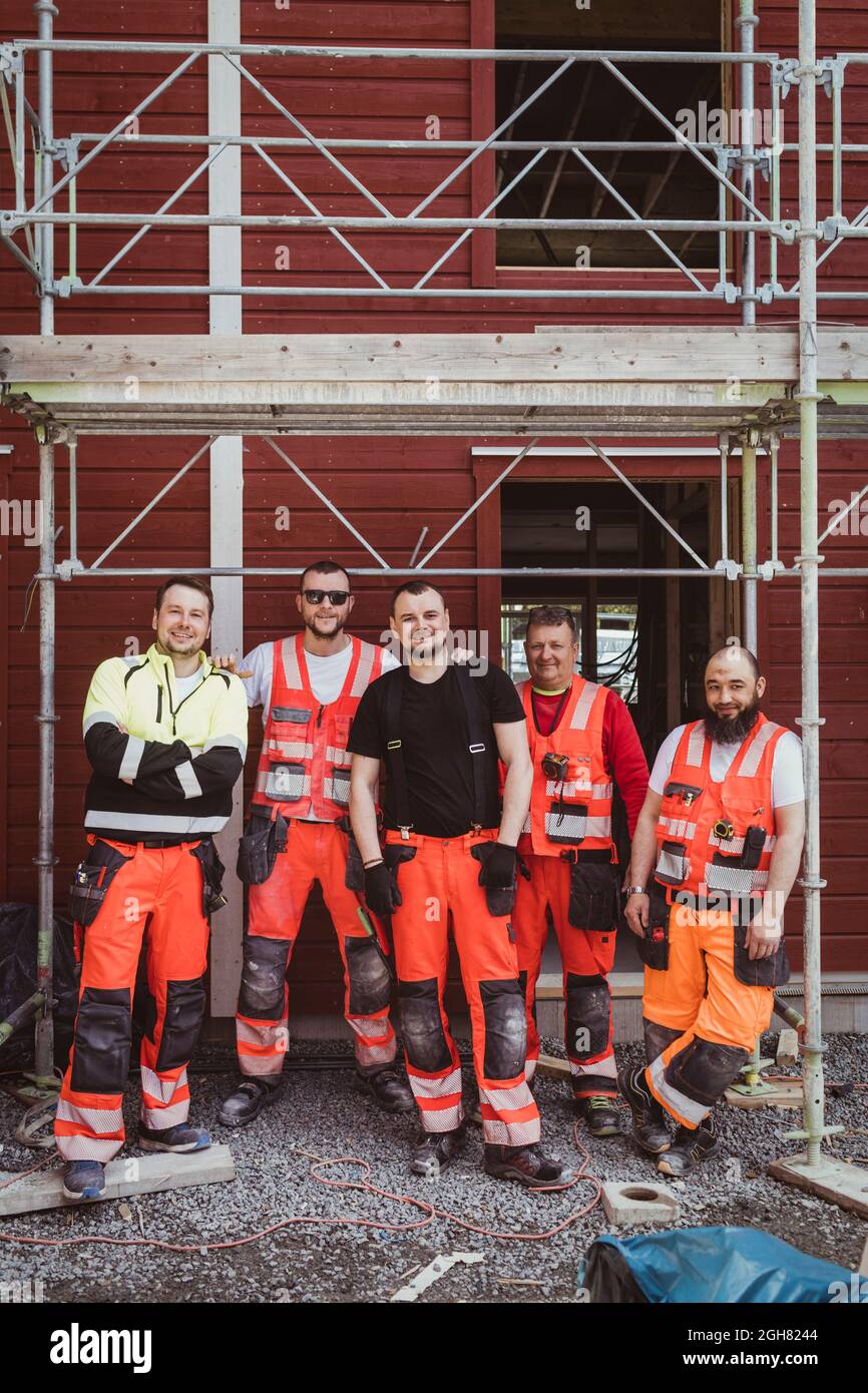 Full length of male construction workers standing together at site Stock Photo