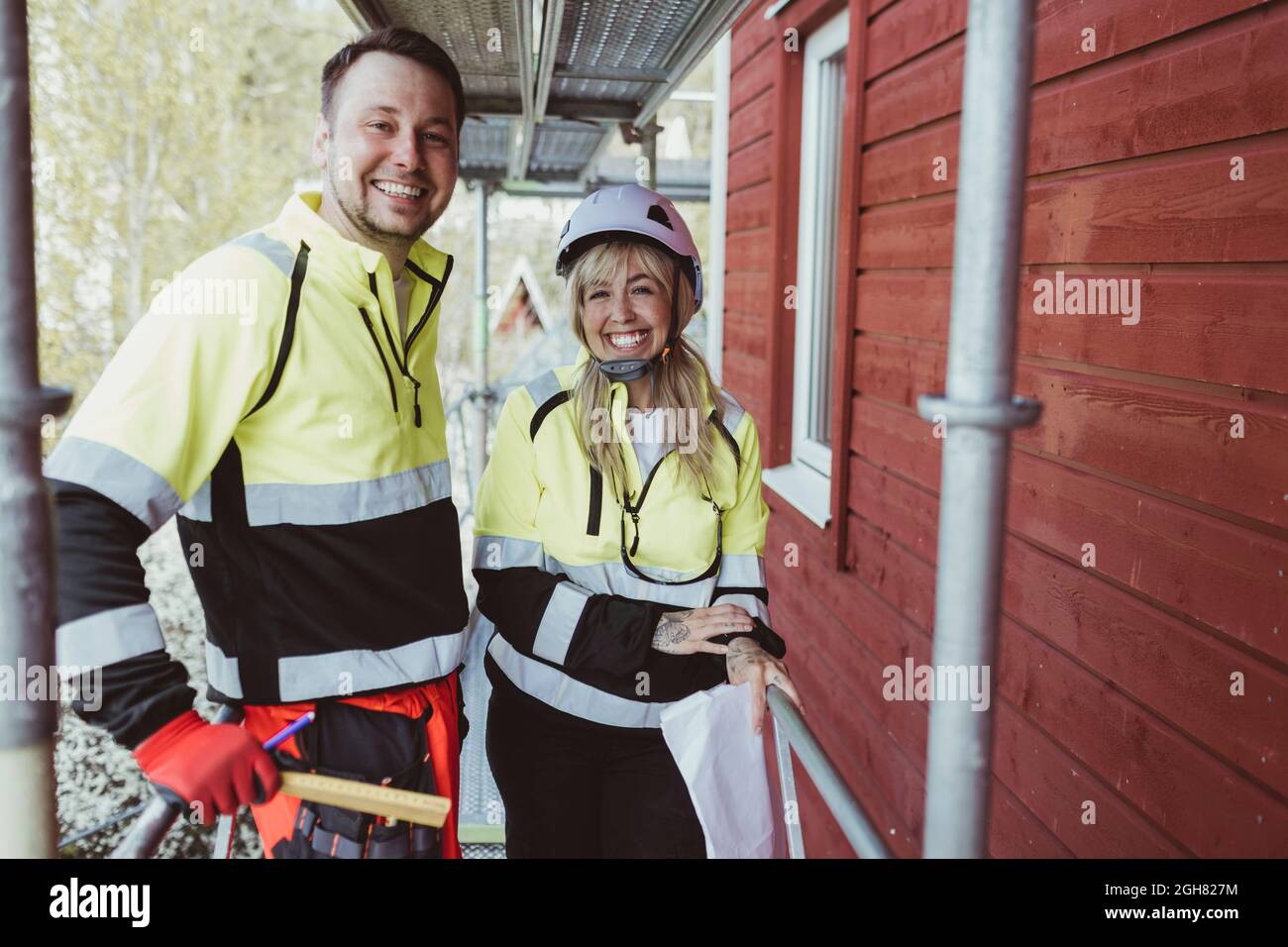 Cheerful male and female colleague standing together at scaffolding Stock Photo