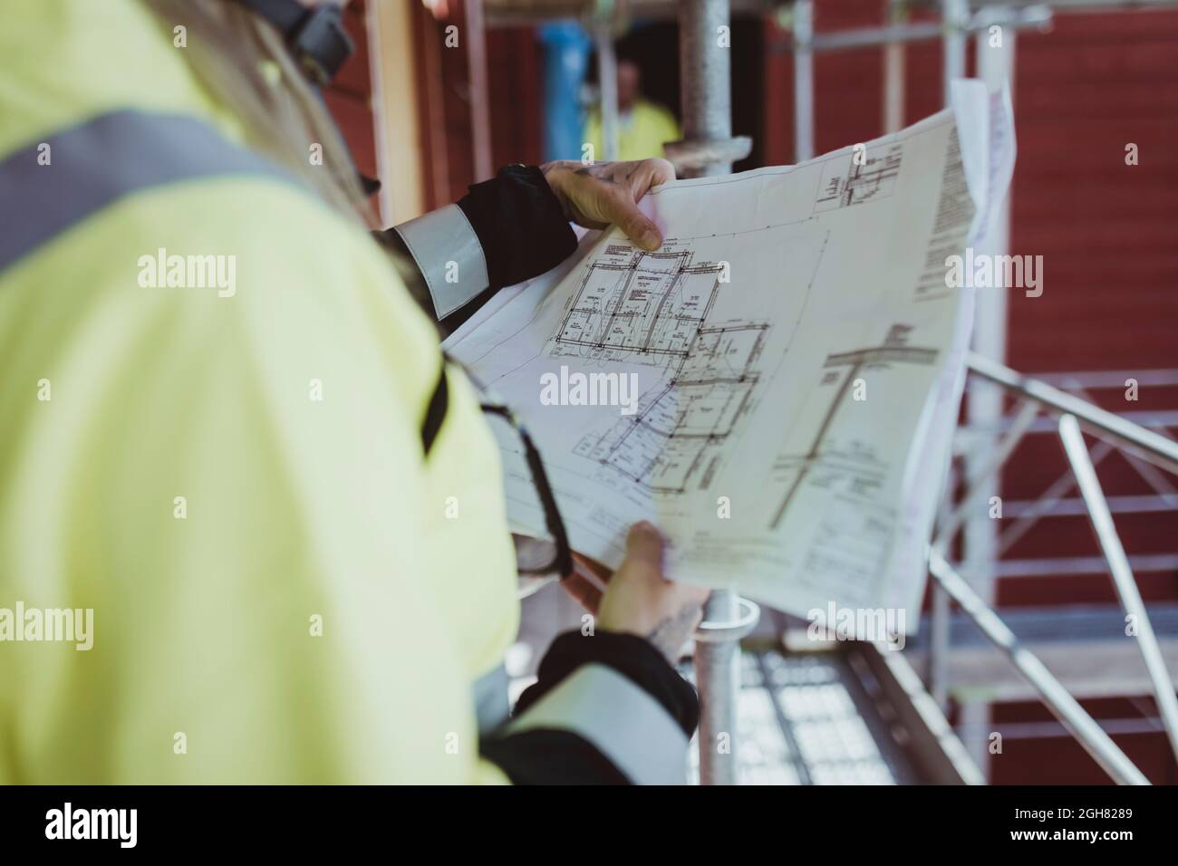 Female building contractor reading floor plan at construction site