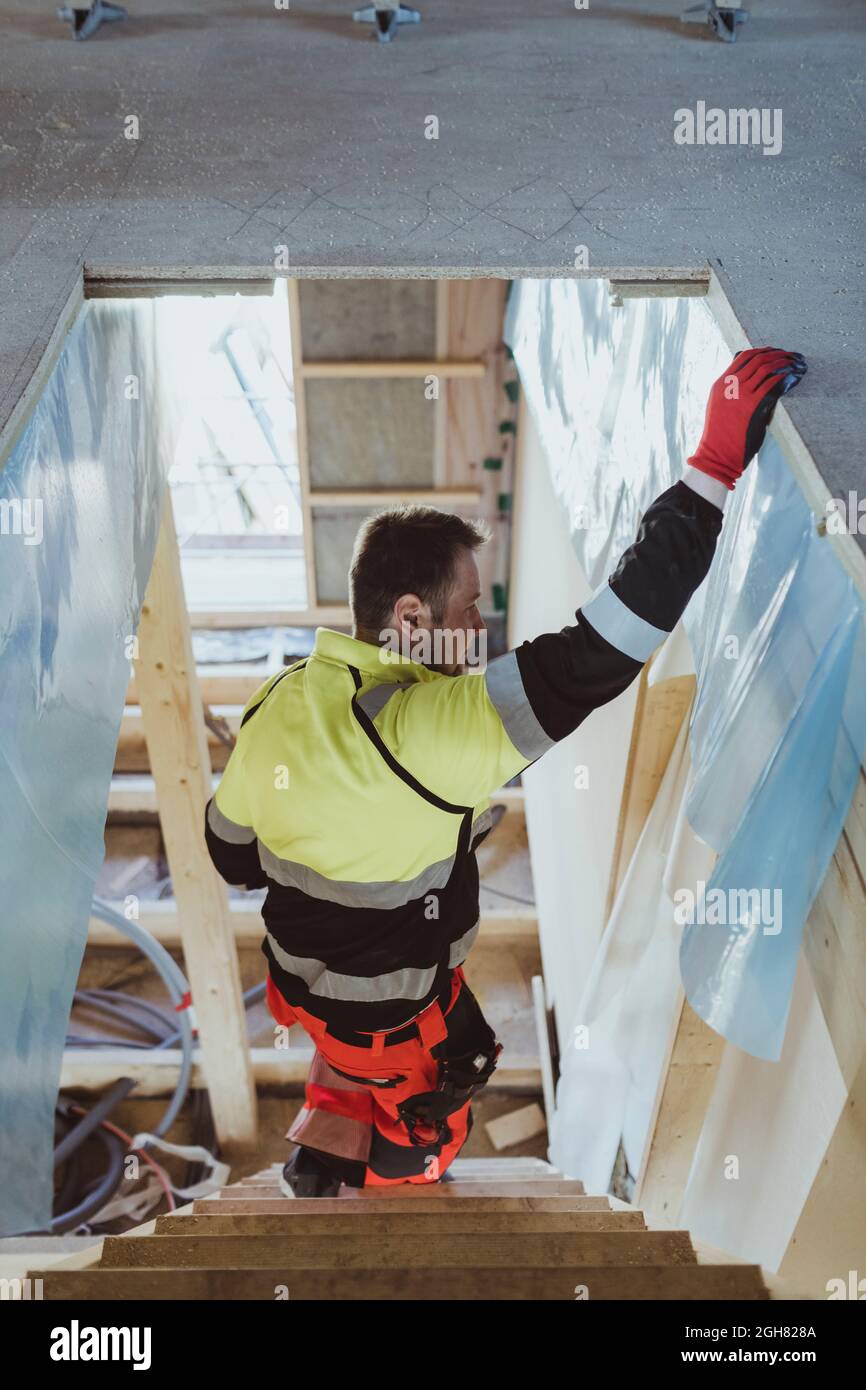Male construction worker moving down steps while working at site Stock Photo