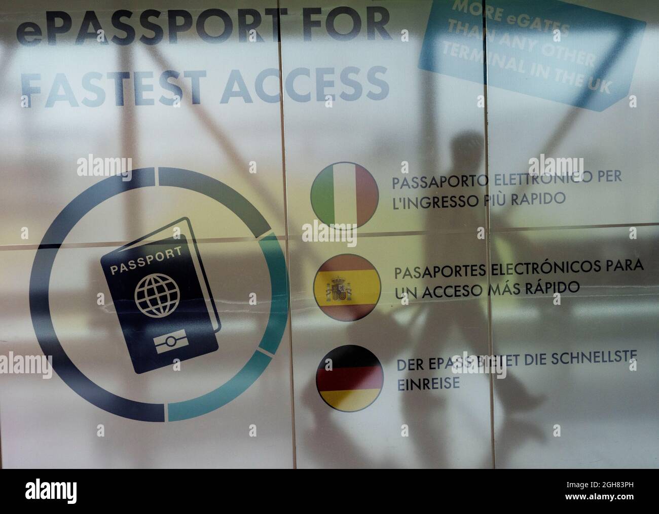 A passenger arrives at Stansted airport, walking past a sign promoting electronic passports. Stock Photo