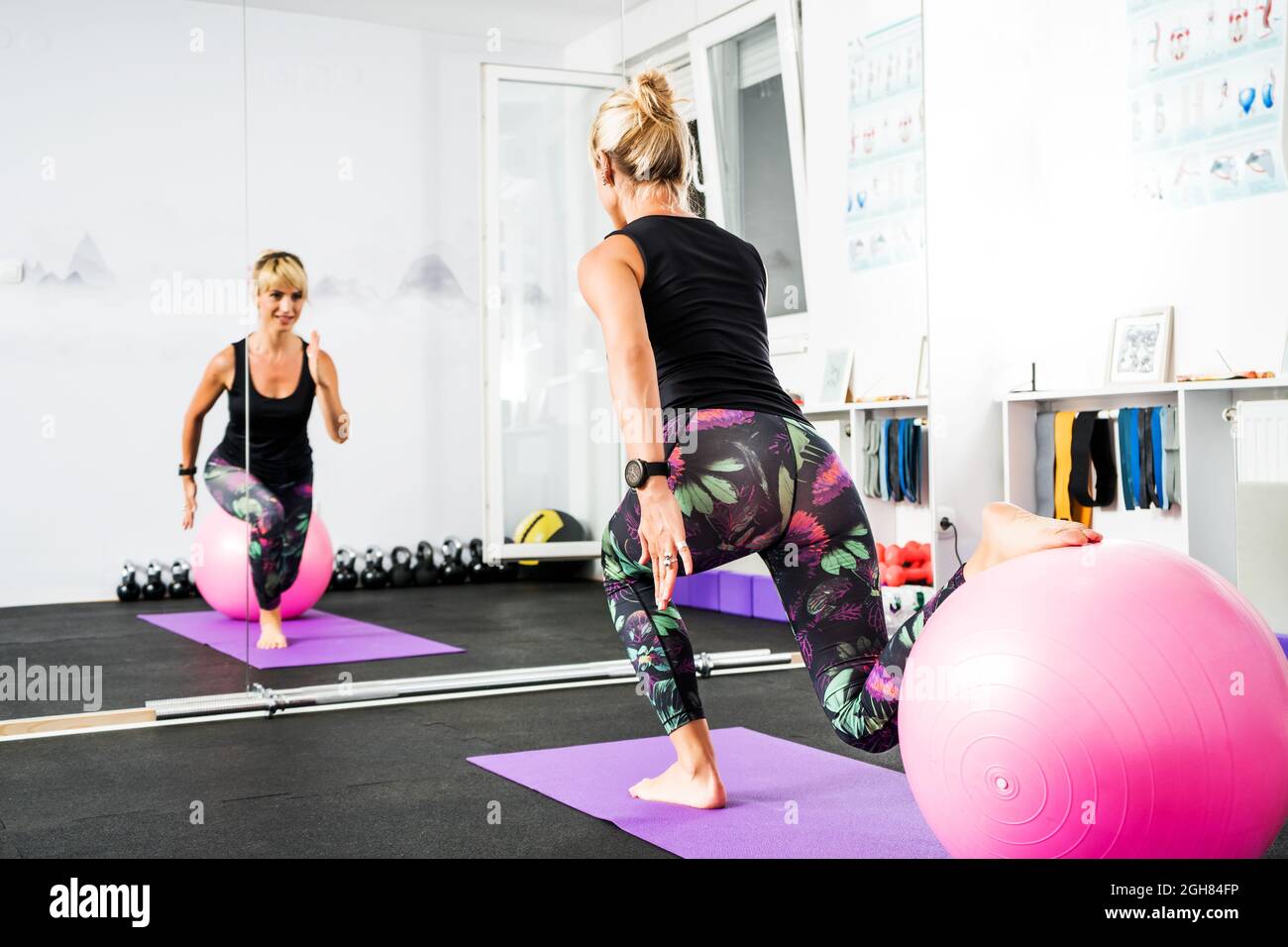 Adult woman is practicing pilates with ball in gym. Stock Photo