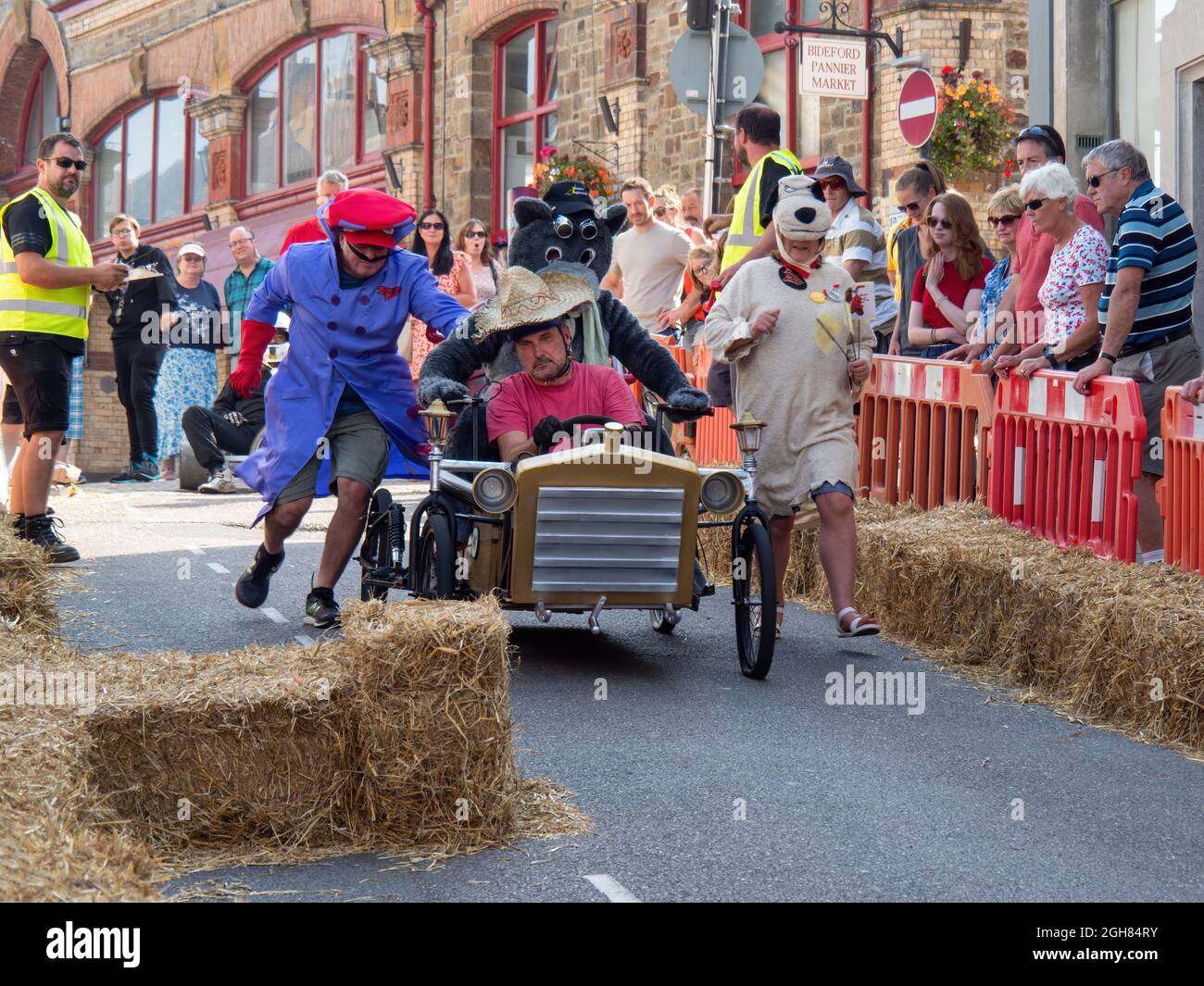 BIDEFORD, NORTH DEVON, ENGLAND - SEPTEMBER 5 2021: The Soapbox Derby - and we're off! Team and cart dressed as wacky races leave the starting line. Stock Photo