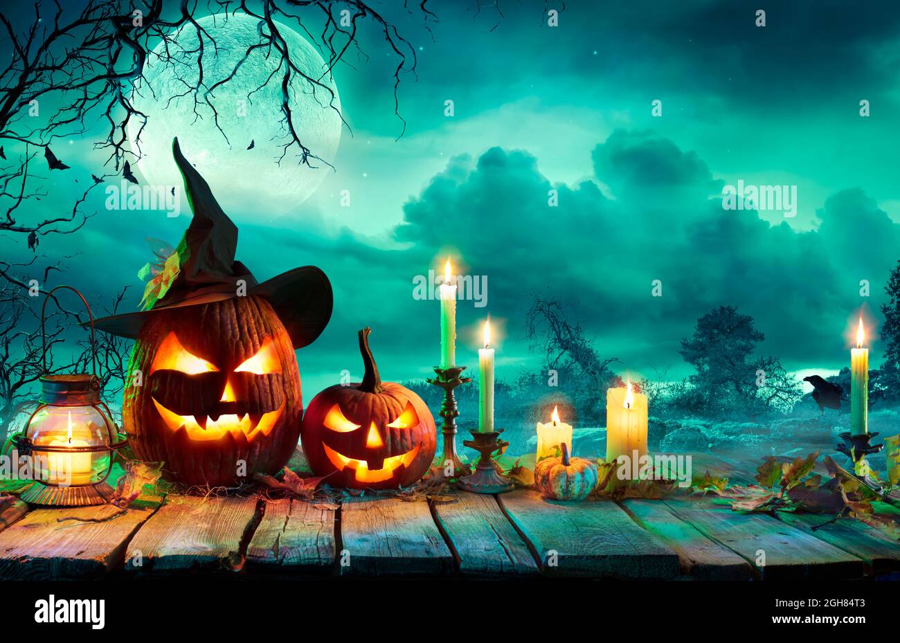 Halloween At Night - Pumpkins With Witch Hat And Candles On Table In Mystery Landscape Stock Photo