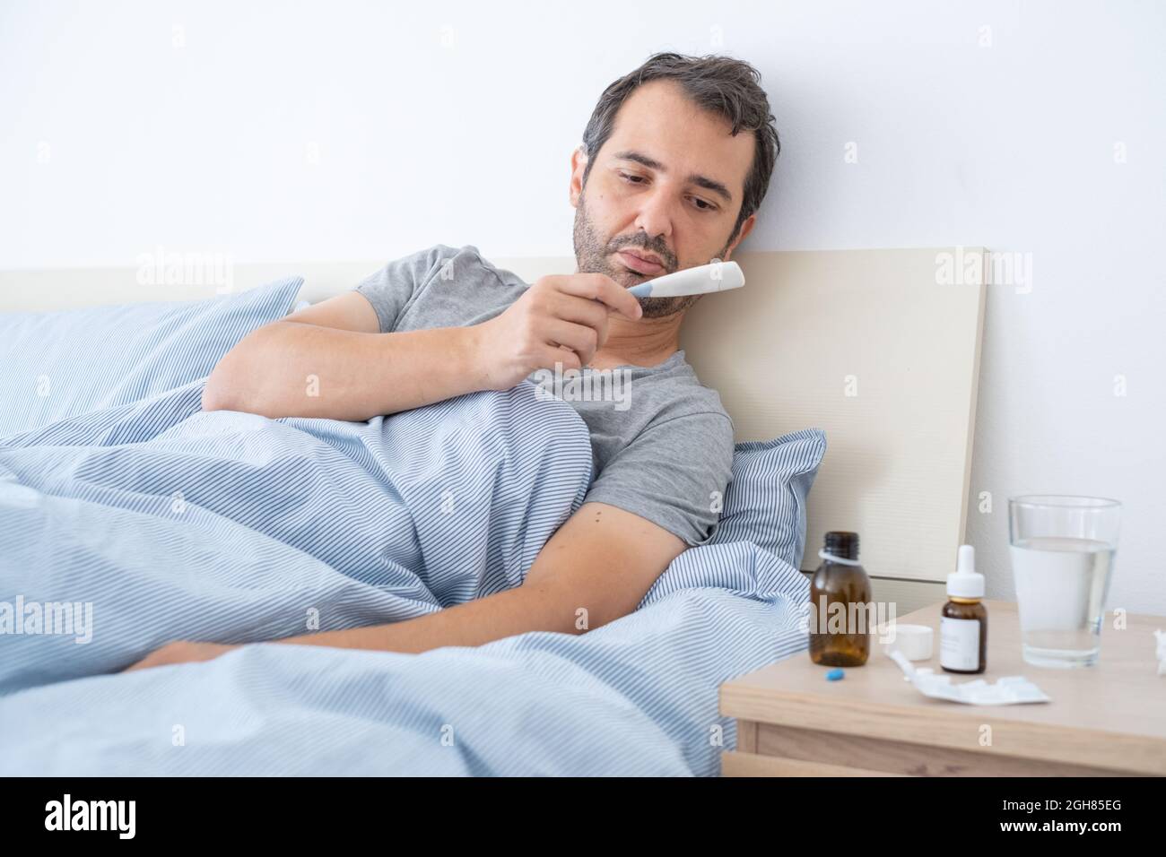 One man affected by cold and flu is looking at the thermometer Stock ...