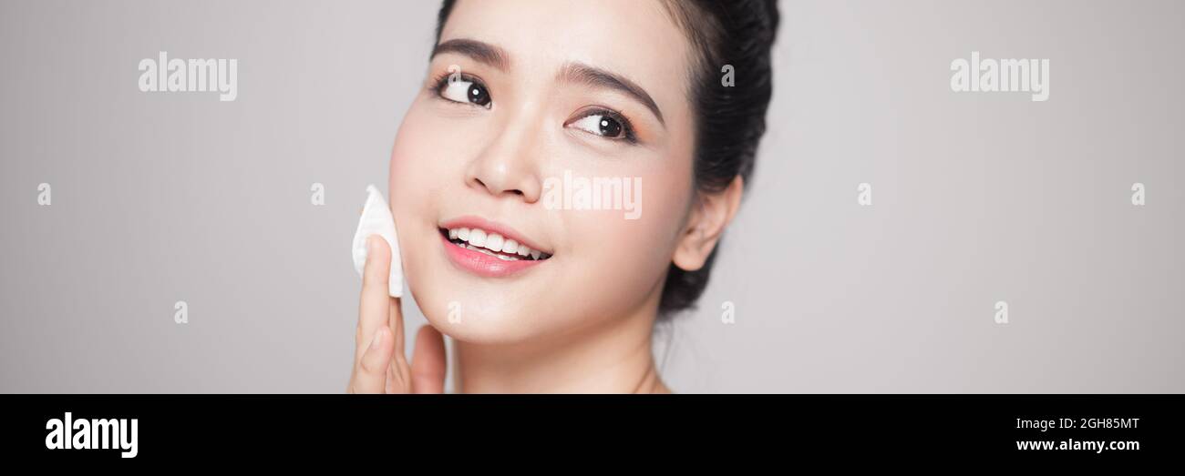 Happy smiling beautiful asian woman using cotton pad cleaning skin ...