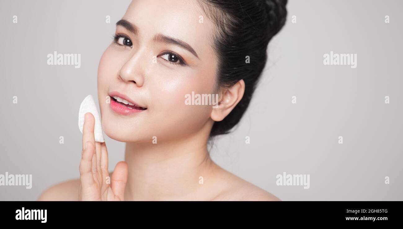 Happy smiling beautiful asian woman using cotton pad cleaning skin ...