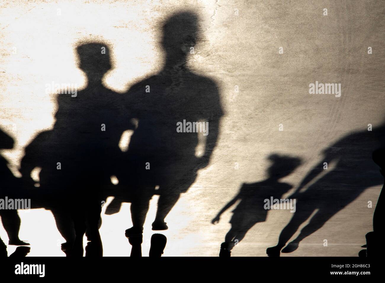 Blurry shadow silhouette of  families walking on a promenade on a summer day, in sepia black and white Stock Photo